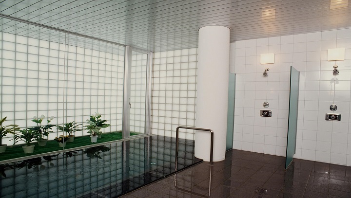 ガラスタイル張りの窓から優しい光が届く、清潔感あふれる造りの大浴場